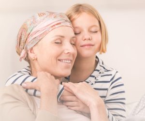 Small caring child embracing her ill mother with headscarf