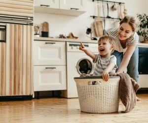 Happy family mother housewife and child son in laundry with washing machine